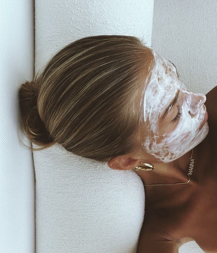 Woman resting with a hydrating face mask and sleek hair