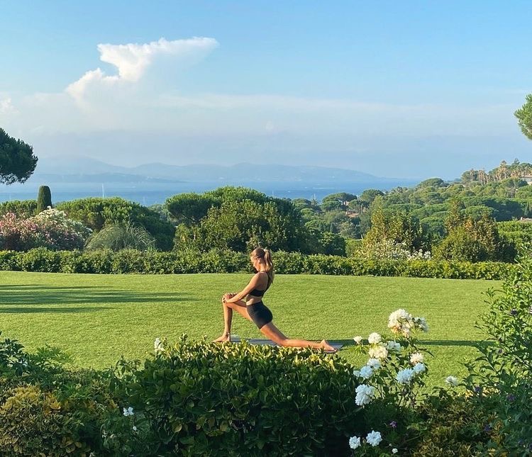 Woman stretching on a green Mediterranean lawn above the sea