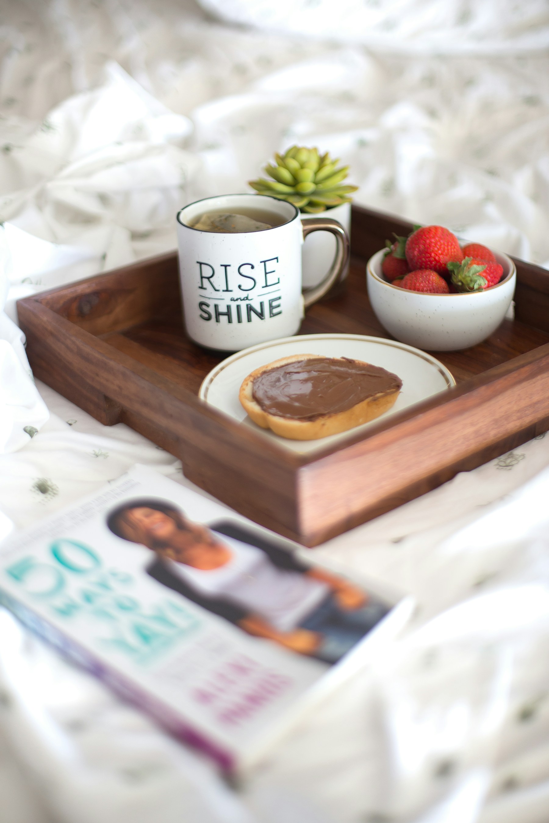 Fruit, breakfast and tea arranged on a white bed tray