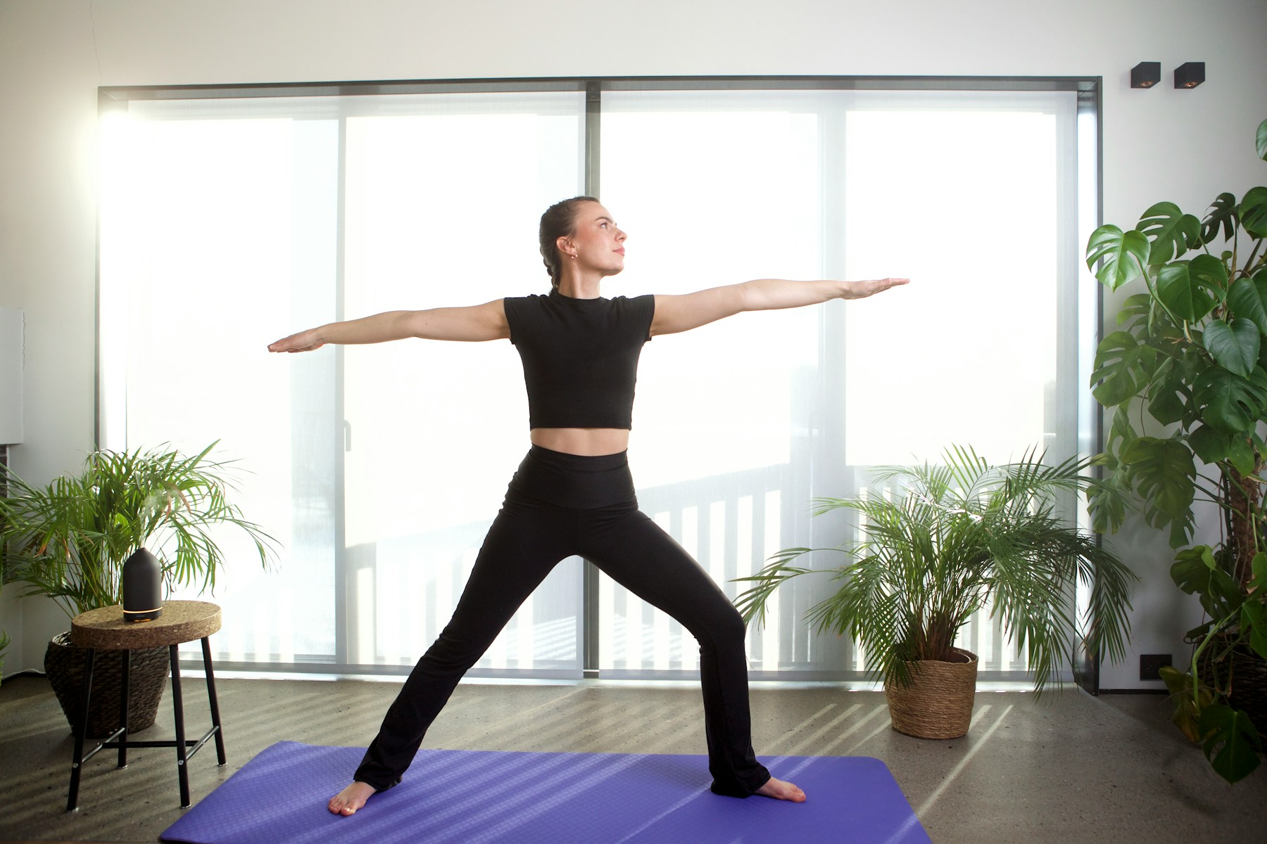 A woman beginning a quiet yoga sequence in a pale studio