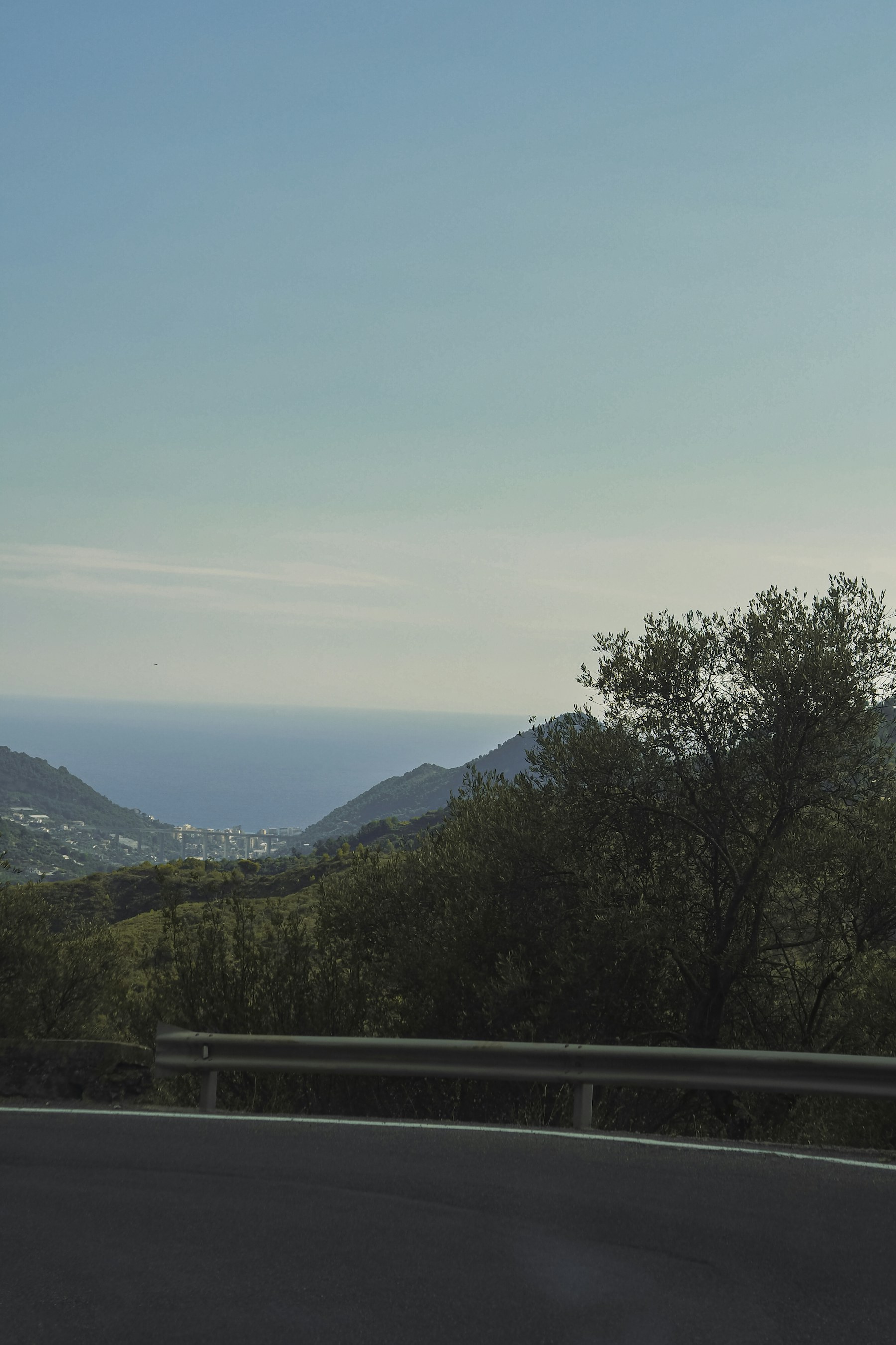 A winding Mediterranean road above green mountains and the sea
